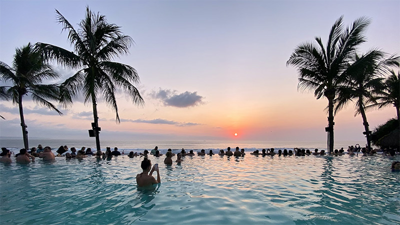Individuals enjoying a swim in a pool with a view of the sunrise