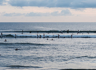 Surfers catching waves in the calm waters of Batu Bolong Beach in Canggu, Bali