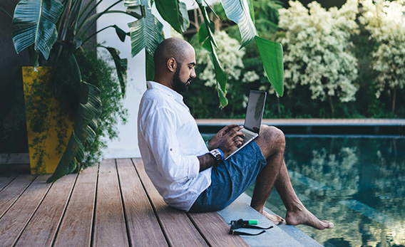 Man working on a laptop by the pool at a tropical villa in Canggu, Bali