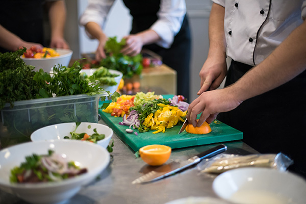 Group cooking class with chefs preparing fresh vegetables