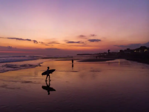 Surfer at dusk on a calm beach