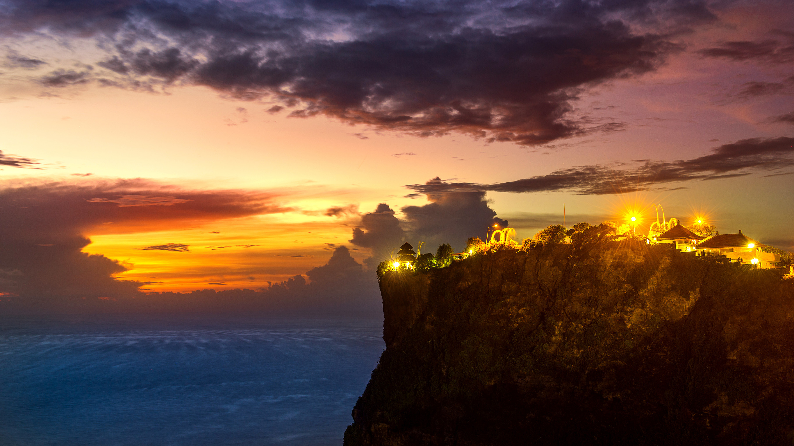 Cliffside with lights against a colorful sunset sky