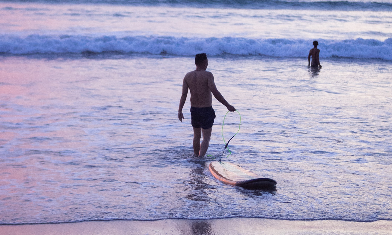 Man heading into the water to surf at the beach