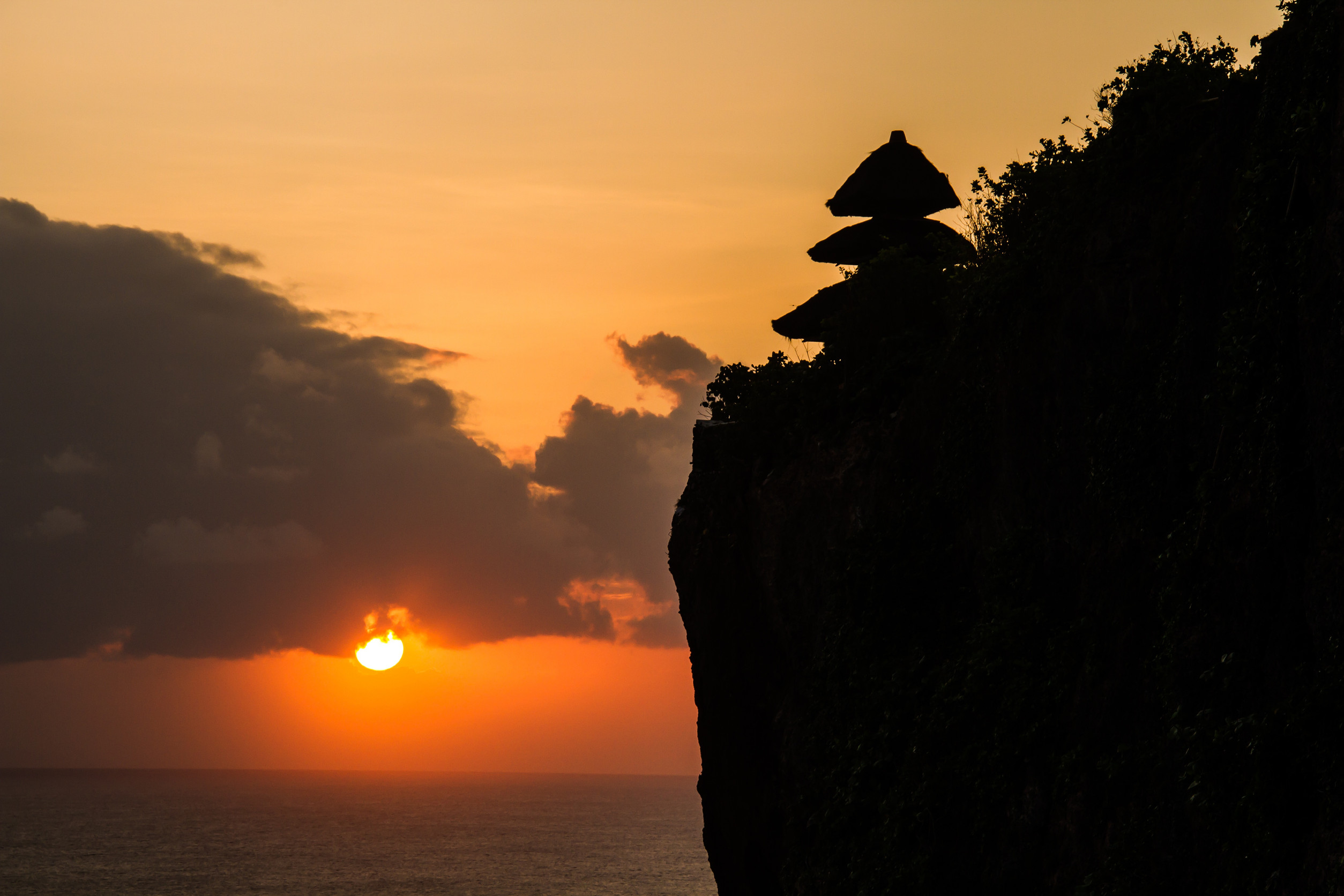 Sunset over the ocean with cliff silhouettes