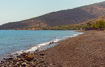 Quiet stretch of rocky beach with distant mountains