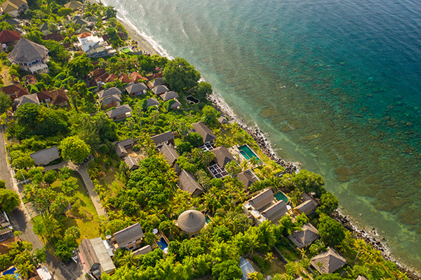Aerial view of Amed village with lush greenery and coastal houses along the shoreline