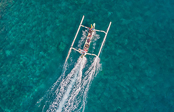Drone view of a boat making waves through turquoise water