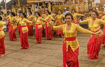 Balinese women in red and yellow costumes dancing in the street