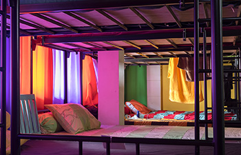 Colorful hostel bunk beds in a dorm room with moody lighting