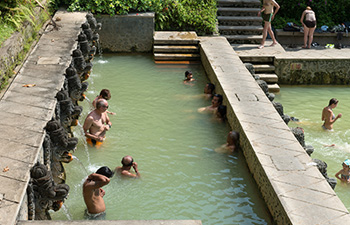 Locals soaking in hot springs with temple-like stone design