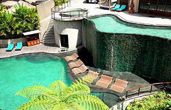 Hotel with green-tile infinity pool and tropical backdrop