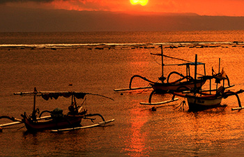 Fishing boats floating on calm waters during sunset