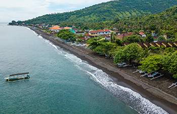 Panoramic view of black sand beach and boats from coastal road