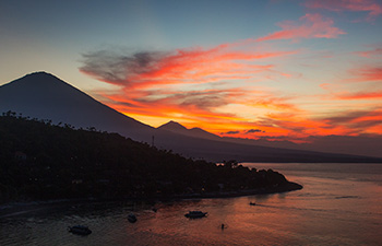 Dramatic sunset over ocean with silhouetted volcano