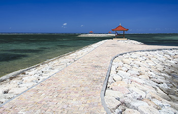 Stone walkway leading to a red-roofed gazebo over the ocean