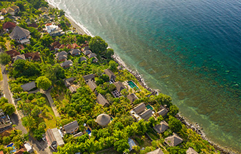 Aerial view of Amed’s coast with beachside villas and trees